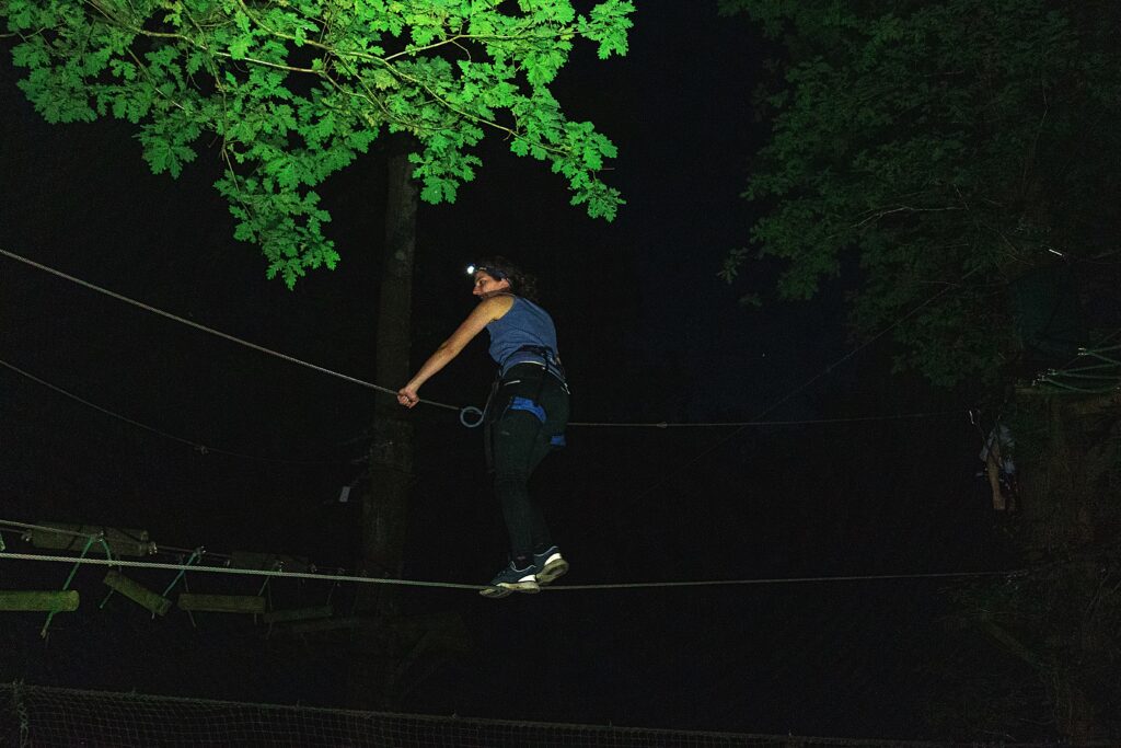 client sur un pont de singe en nocturne accrobranche